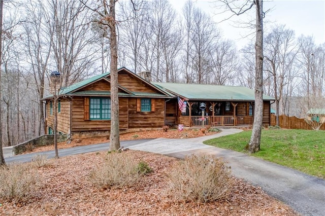 log-style house featuring covered porch and a front yard