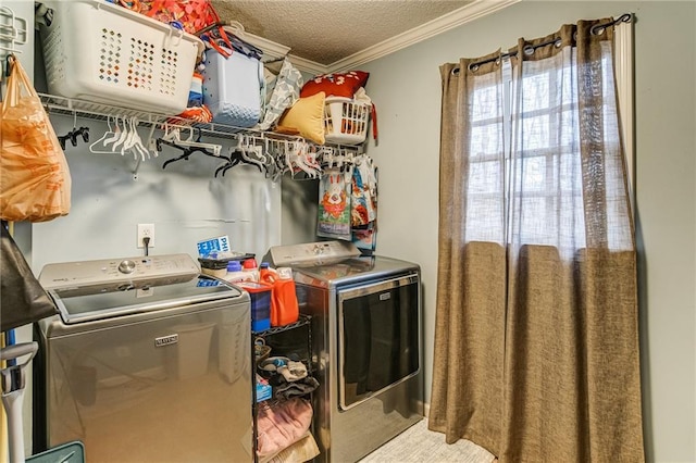 clothes washing area with washer and dryer, a textured ceiling, and crown molding