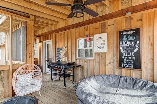 interior space featuring beam ceiling, ceiling fan, light wood-type flooring, and plenty of natural light