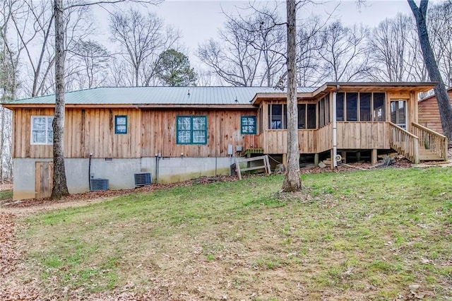 rear view of house featuring a lawn, a sunroom, and central AC unit