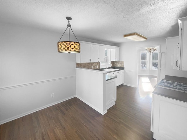 kitchen featuring backsplash, dark hardwood / wood-style floors, pendant lighting, sink, and white cabinets