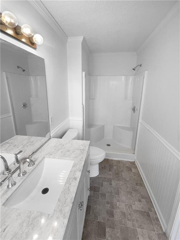 bathroom with toilet, vanity, a shower, and a textured ceiling