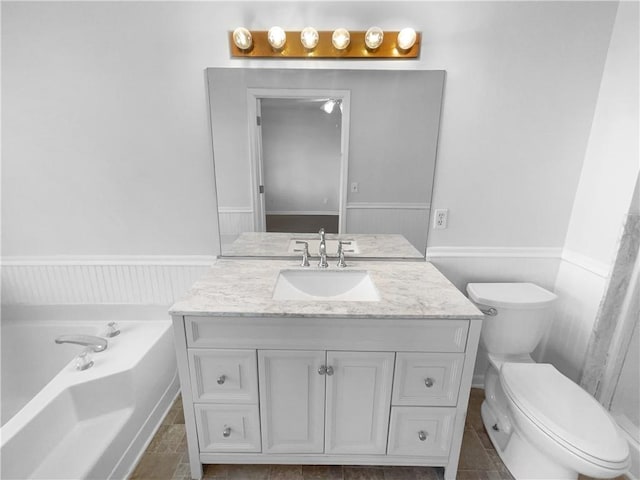 bathroom featuring toilet, vanity, tile patterned floors, and a bathing tub