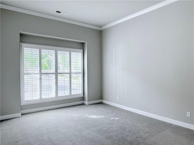 carpeted spare room with baseboards, crown molding, and visible vents