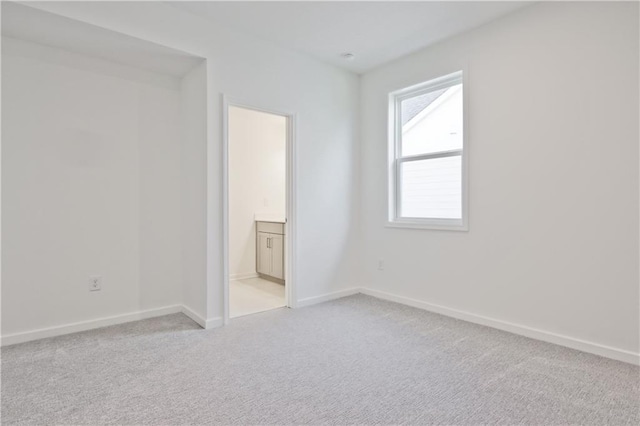 unfurnished bedroom featuring light colored carpet and ensuite bath