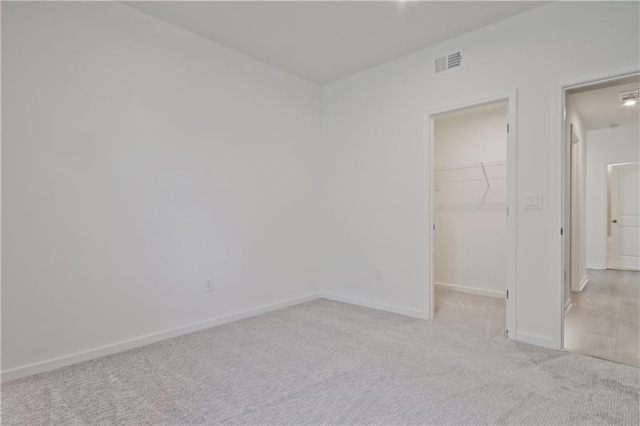 unfurnished bedroom with light colored carpet, a closet, and a spacious closet