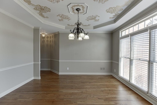 spare room featuring dark hardwood / wood-style flooring, ornamental molding, an inviting chandelier, and a tray ceiling