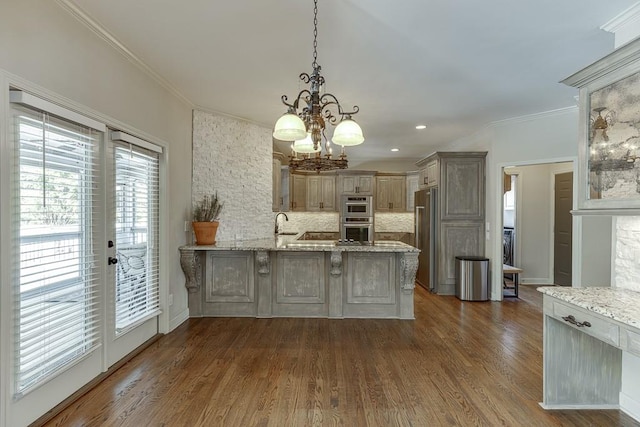 kitchen with a breakfast bar area, hanging light fixtures, ornamental molding, kitchen peninsula, and stainless steel appliances