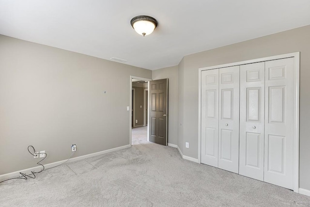 unfurnished bedroom featuring light colored carpet and a closet