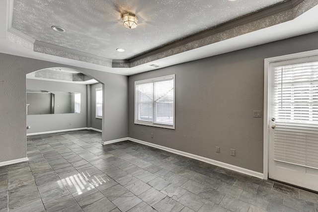 unfurnished room with plenty of natural light and a tray ceiling