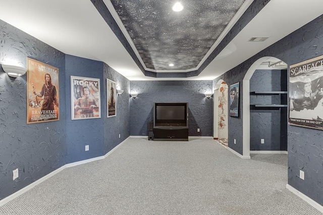 home theater room featuring crown molding, a tray ceiling, and carpet floors