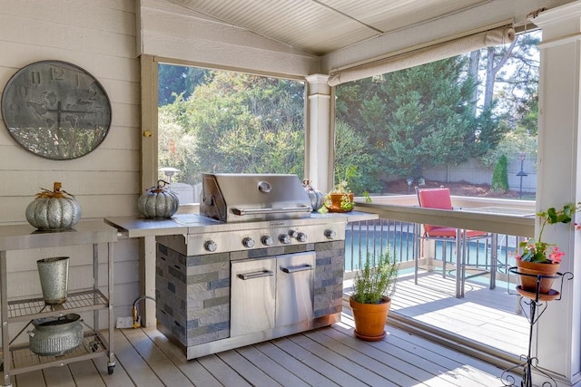 wooden deck featuring a pool, an outdoor kitchen, and a grill