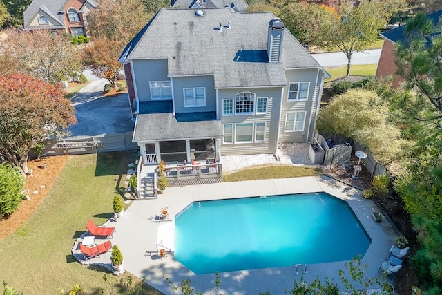 rear view of property featuring a fenced in pool, a lawn, and a sunroom