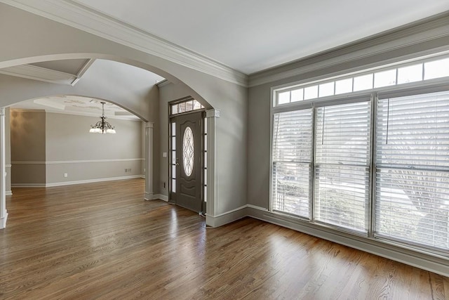 foyer with an inviting chandelier, ornamental molding, and dark hardwood / wood-style floors