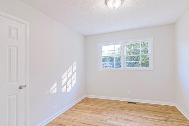 unfurnished room featuring light hardwood / wood-style flooring and a textured ceiling