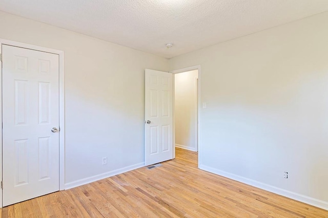 unfurnished room featuring light hardwood / wood-style floors and a textured ceiling