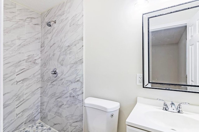 bathroom featuring tiled shower, vanity, and toilet