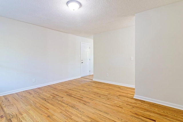 unfurnished room with a textured ceiling and light wood-type flooring