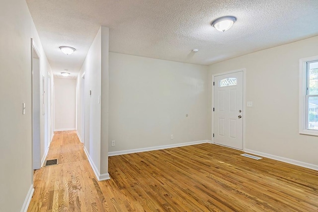 foyer entrance with a textured ceiling and light hardwood / wood-style flooring