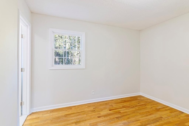 spare room featuring light hardwood / wood-style flooring and a textured ceiling