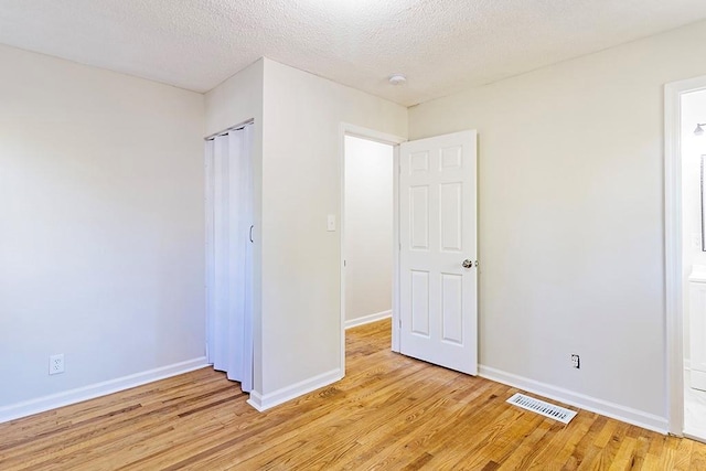 unfurnished bedroom with a textured ceiling and light wood-type flooring