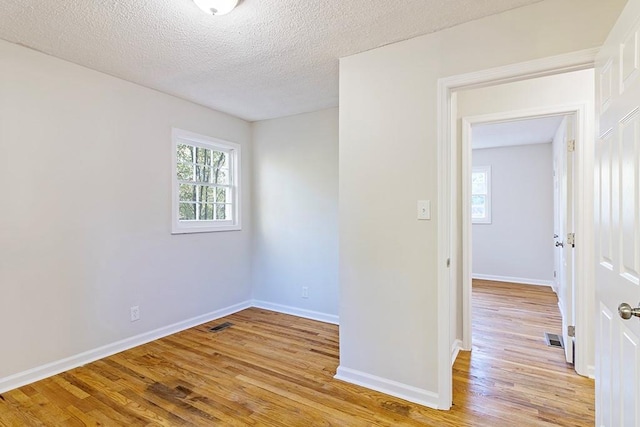 spare room featuring a textured ceiling and light hardwood / wood-style floors