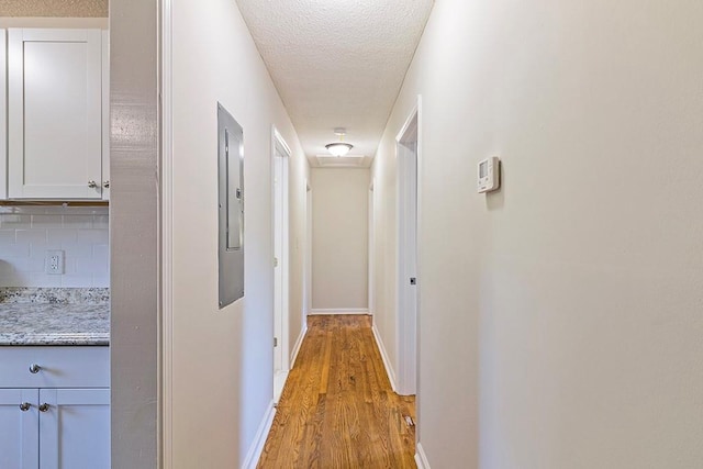 hallway featuring light hardwood / wood-style floors and a textured ceiling