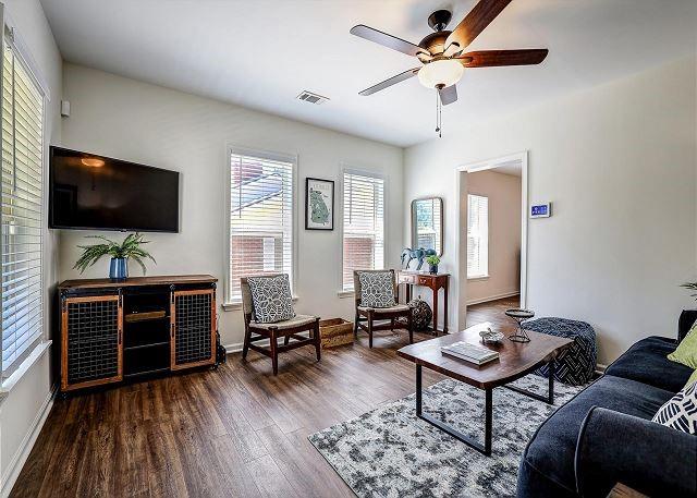 living area featuring visible vents, ceiling fan, baseboards, and wood finished floors