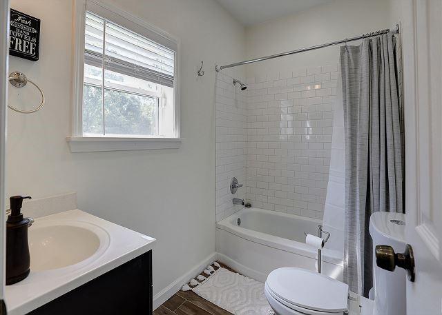 full bathroom with shower / bathtub combination with curtain, toilet, vanity, wood finished floors, and baseboards