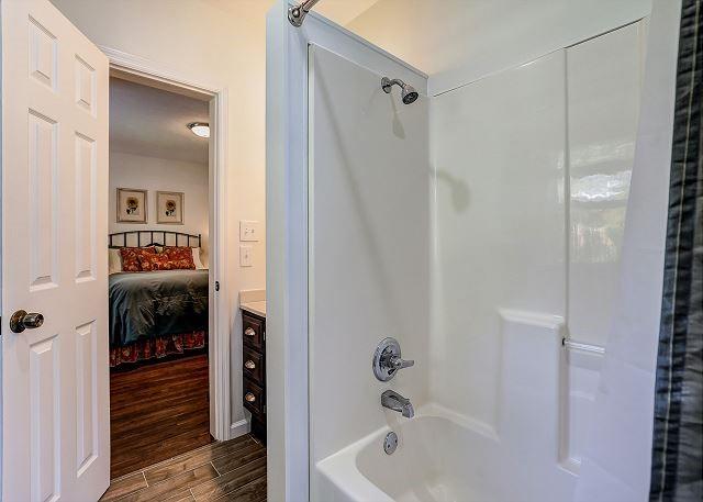 ensuite bathroom featuring ensuite bath, wood finished floors, and bathing tub / shower combination