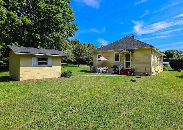 back of property featuring entry steps, concrete block siding, and a lawn