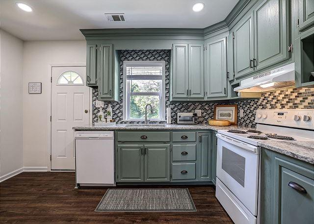 kitchen with white appliances, a sink, dark wood finished floors, and under cabinet range hood