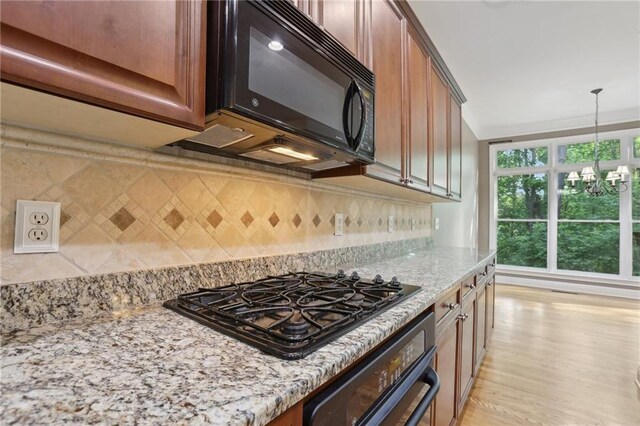 1215 Comet View Trl SE, Smyrna, GA 30082 - kitchen featuring decorative backsplash, light stone countertops, black appliances, light wood finished floors, and a notable chandelier