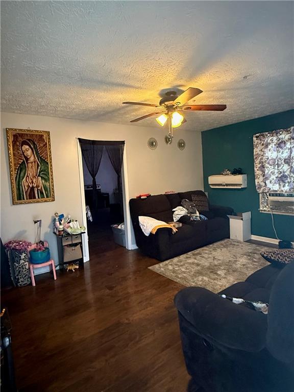 living room with ceiling fan, cooling unit, a textured ceiling, and dark hardwood / wood-style flooring