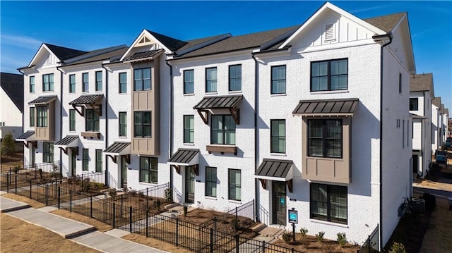 506 Healy Dr Unit 74, Cumming, GA 30040 - townhome / multi-family property with a standing seam roof, brick siding, a fenced front yard, and metal roof