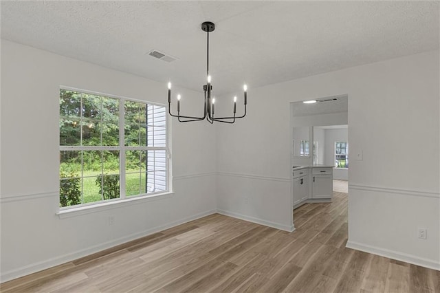 1069 Alford Rd, Lithonia, GA 30058 - unfurnished dining area with a chandelier, light wood-style floors, plenty of natural light, and a textured ceiling