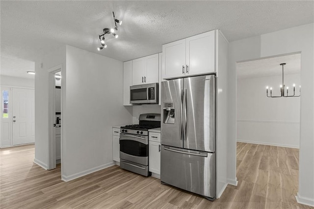 1069 Alford Rd, Lithonia, GA 30058 - kitchen featuring appliances with stainless steel finishes, light wood finished floors, a chandelier, white cabinets, and a textured ceiling