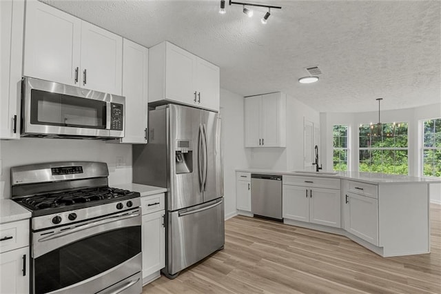 1069 Alford Rd, Lithonia, GA 30058 - kitchen featuring stainless steel appliances, a peninsula, light countertops, white cabinets, and a textured ceiling