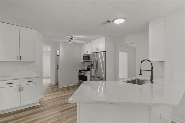 1069 Alford Rd, Lithonia, GA 30058 - kitchen with stainless steel appliances, a peninsula, light wood-type flooring, white cabinets, and a textured ceiling