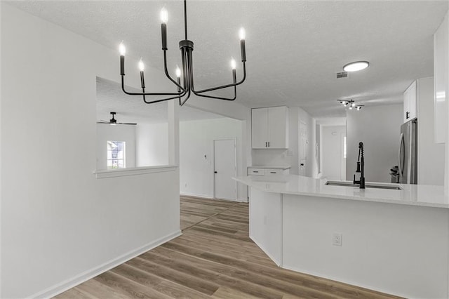 1069 Alford Rd, Lithonia, GA 30058 - kitchen featuring a textured ceiling, freestanding refrigerator, light countertops, white cabinets, and a chandelier