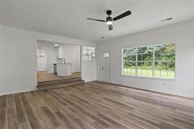 1069 Alford Rd, Lithonia, GA 30058 - unfurnished living room with a chandelier, wood finished floors, a textured ceiling, and ceiling fan