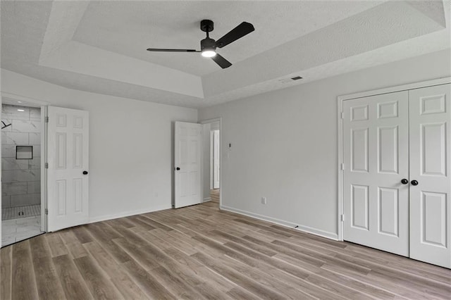 1069 Alford Rd, Lithonia, GA 30058 - unfurnished bedroom featuring a raised ceiling, light wood-type flooring, a textured ceiling, ensuite bathroom, and ceiling fan