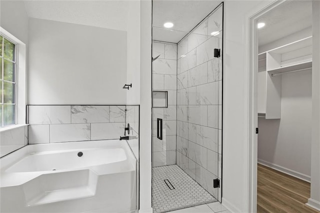 1069 Alford Rd, Lithonia, GA 30058 - full bath featuring a garden tub, a shower stall, a walk in closet, recessed lighting, and wood finished floors