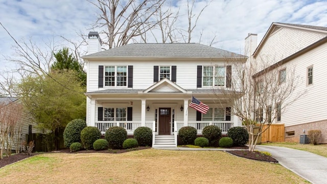 view of front of home featuring central AC unit, a chimney, a porch, and a front yard