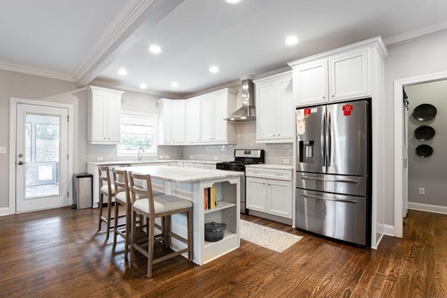 kitchen with a center island, dark wood-style flooring, appliances with stainless steel finishes, ornamental molding, and wall chimney exhaust hood