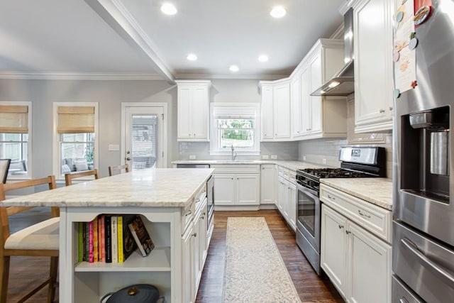 kitchen with stainless steel appliances, backsplash, ornamental molding, a sink, and a kitchen bar