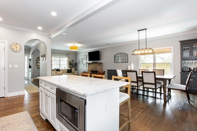 kitchen with dark wood-style floors, a center island, stainless steel microwave, and plenty of natural light