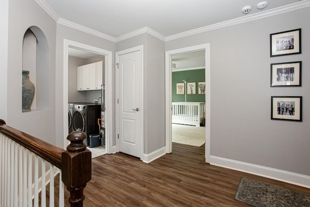 hall with baseboards, dark wood finished floors, ornamental molding, independent washer and dryer, and an upstairs landing