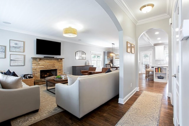 living area with baseboards, arched walkways, ornamental molding, dark wood-style flooring, and a fireplace