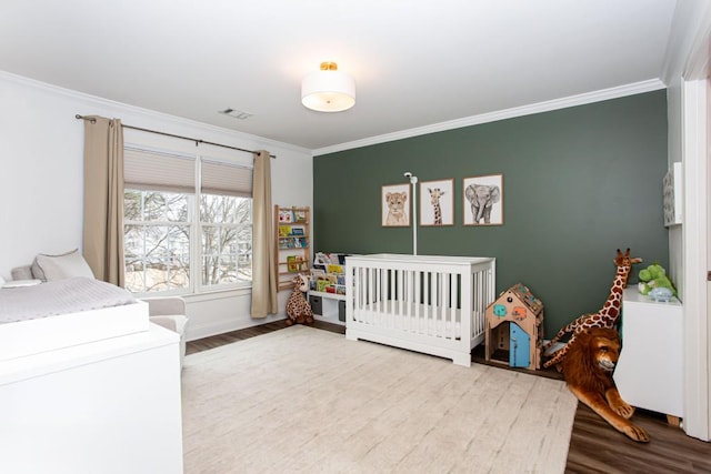 bedroom featuring visible vents, crown molding, and wood finished floors